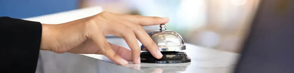 Close up of person's hand ringing front desk check in bell